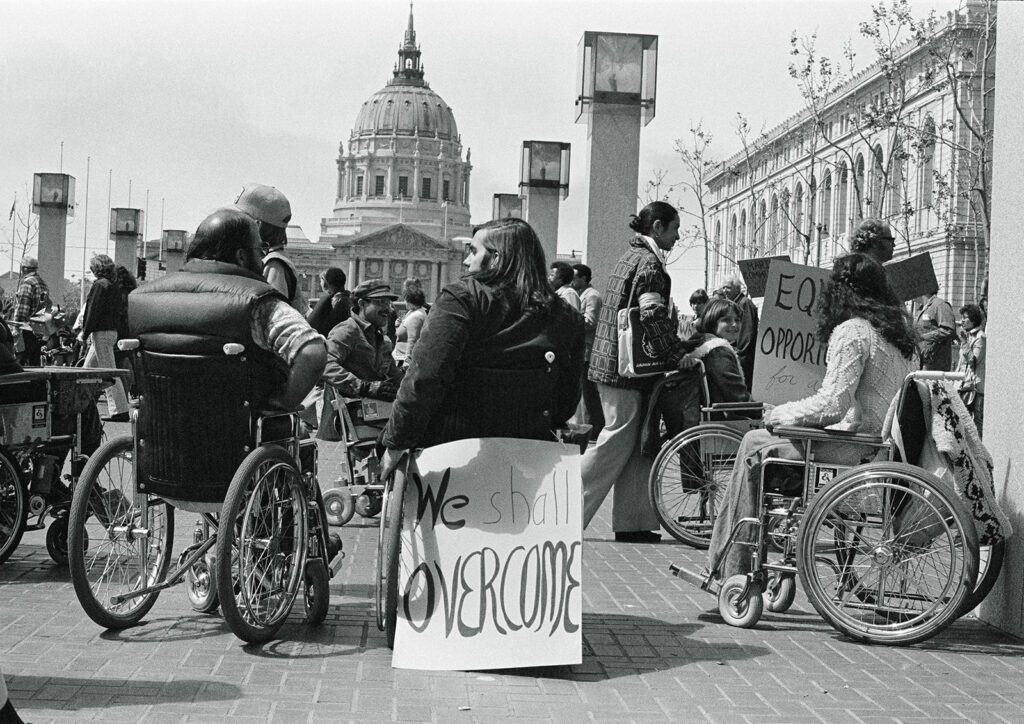 A group of protesters, some of them using wheelchairs, sit outside the federal building in San Francisco.