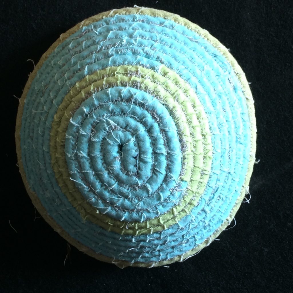 Blue bowl made from fabric wrapped around rope and coiled together.