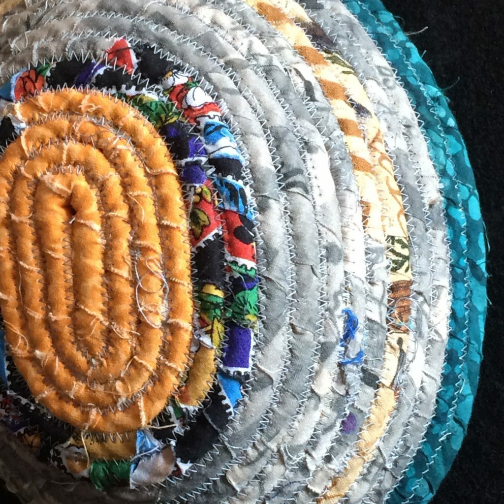 Orange, black, white, and Blue bowl made from fabric wrapped around rope and coiled together.