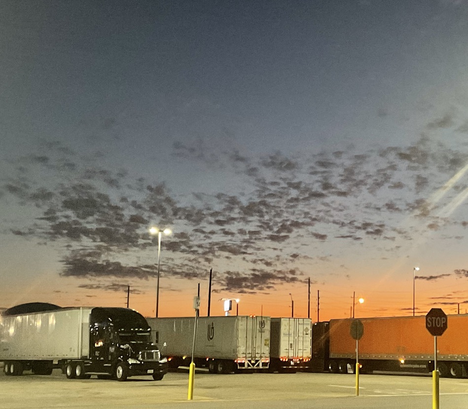 photo of trucks parked closely together with the sun setting behind them